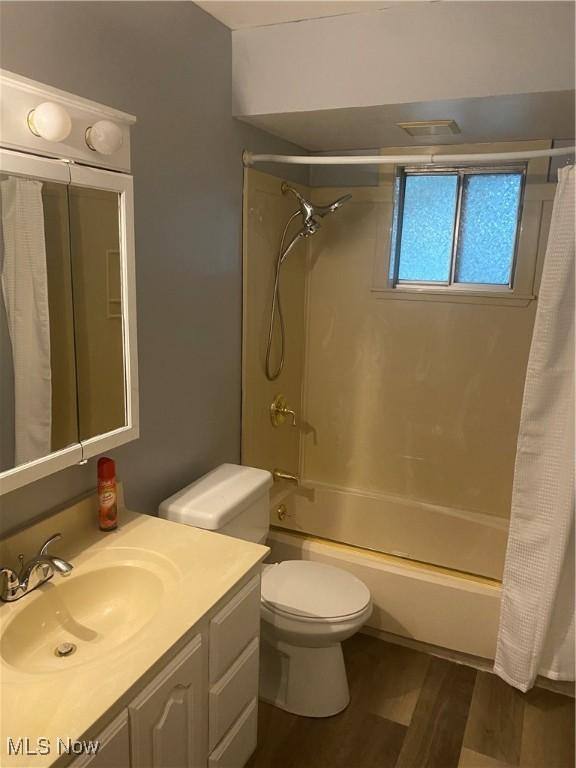 full bathroom with wood-type flooring, shower / bath combo, vanity, and toilet