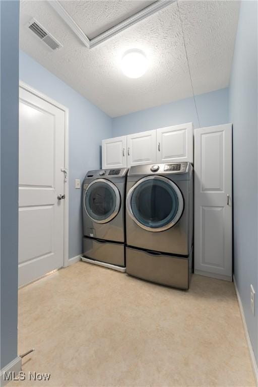 washroom featuring cabinets, washing machine and dryer, and a textured ceiling