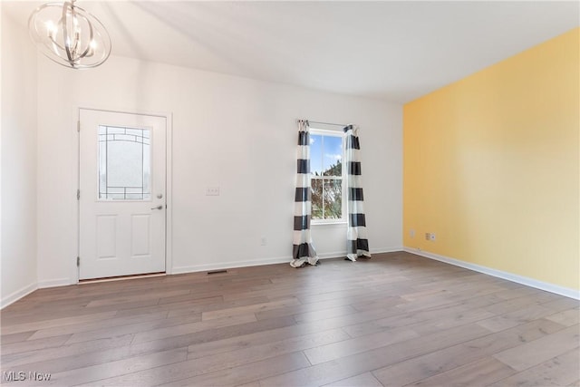 empty room featuring an inviting chandelier and hardwood / wood-style flooring