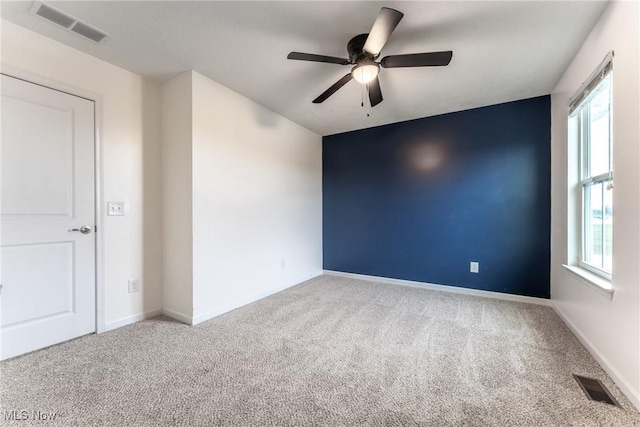 empty room featuring ceiling fan and carpet