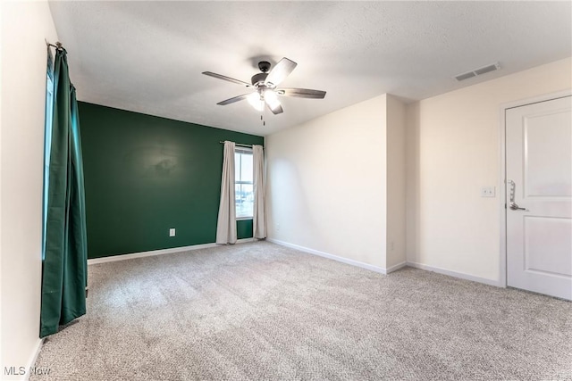 carpeted spare room with a textured ceiling and ceiling fan