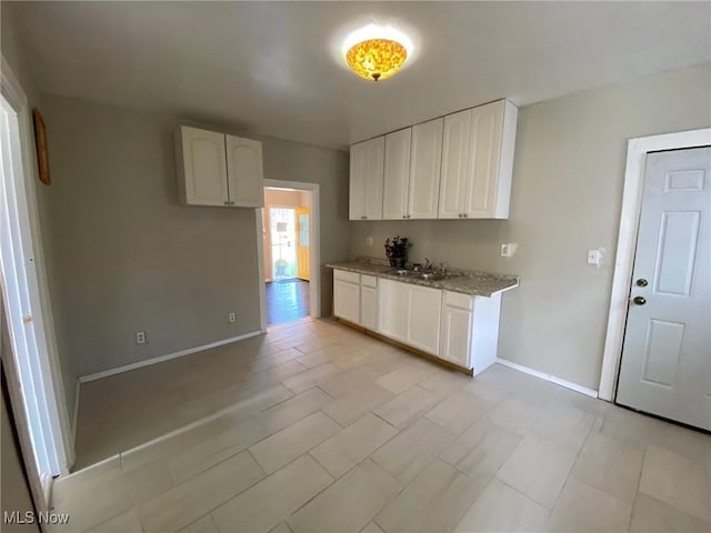 kitchen with light stone countertops, sink, and white cabinets