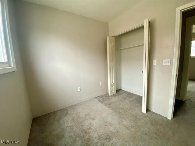 unfurnished bedroom featuring light colored carpet and a closet