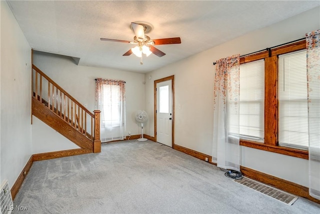 foyer entrance with light colored carpet and ceiling fan