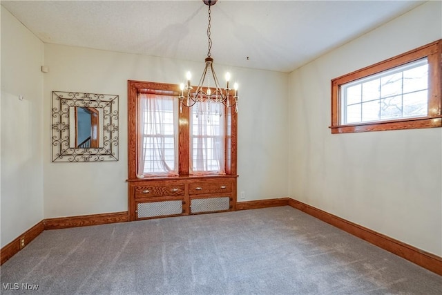 carpeted empty room featuring a chandelier