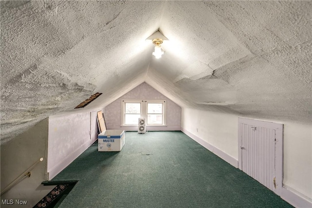 bonus room featuring dark carpet, vaulted ceiling, and a textured ceiling