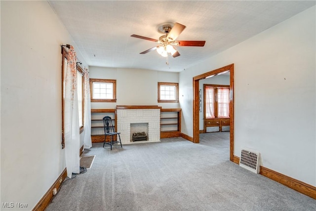 unfurnished living room with light carpet, a brick fireplace, and ceiling fan