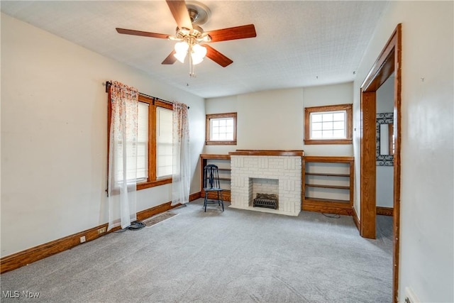 unfurnished living room with ceiling fan, carpet flooring, and a fireplace