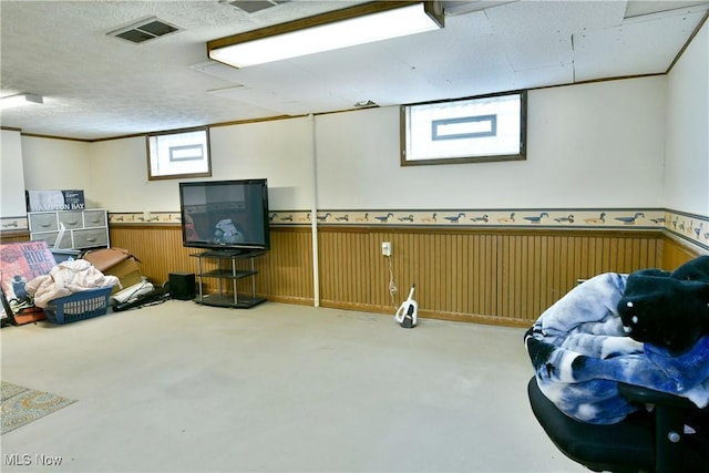 basement featuring a textured ceiling and wood walls