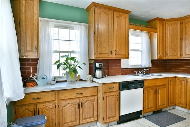 kitchen with tasteful backsplash, white dishwasher, light tile patterned flooring, and sink