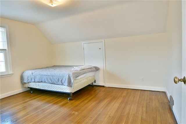 bedroom featuring multiple windows, hardwood / wood-style flooring, and lofted ceiling