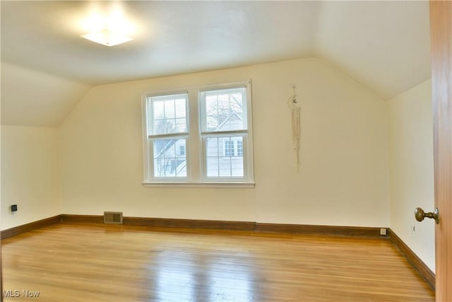 additional living space with vaulted ceiling and light hardwood / wood-style floors