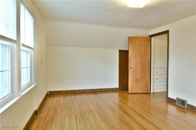 additional living space featuring lofted ceiling and light wood-type flooring