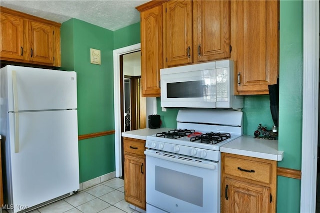 kitchen featuring light tile patterned floors, a textured ceiling, and white appliances