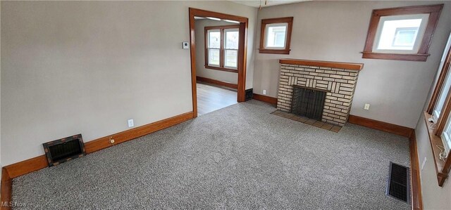 1151 Bedford Ave SW, Canton, OH 44710 - unfurnished living room featuring a brick fireplace, visible vents, carpet, and baseboards