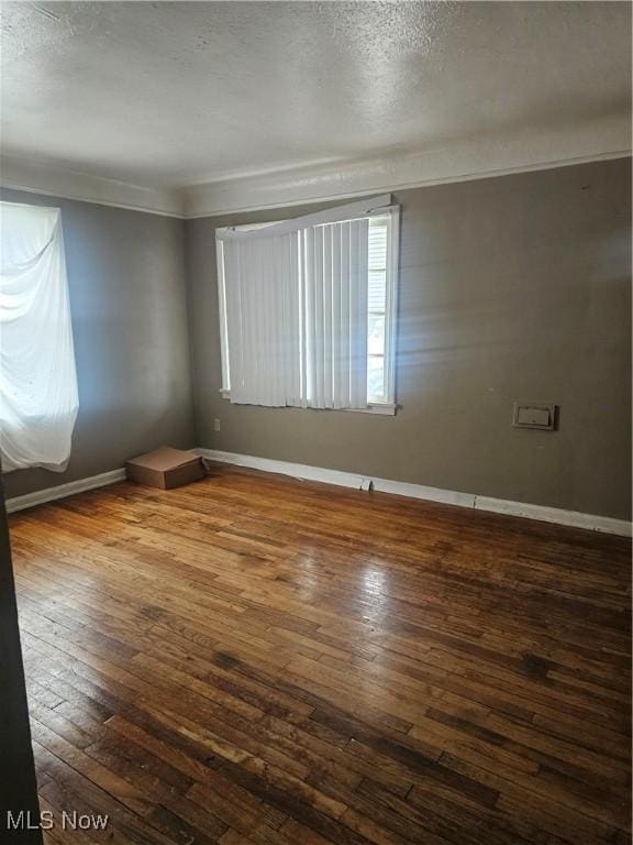 spare room with crown molding, wood-type flooring, and a textured ceiling