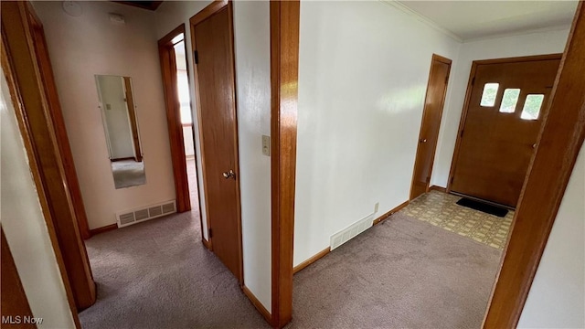 hall with ornamental molding and light colored carpet