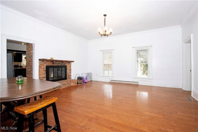 living room featuring crown molding, light wood-type flooring, a notable chandelier, a fireplace, and a baseboard heating unit