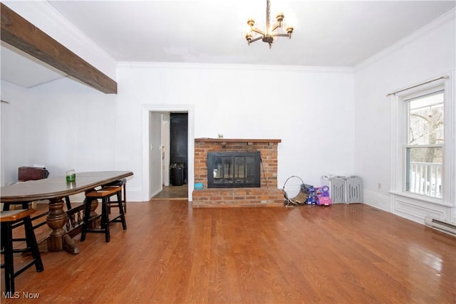 living room featuring radiator, hardwood / wood-style floors, a fireplace, a notable chandelier, and crown molding