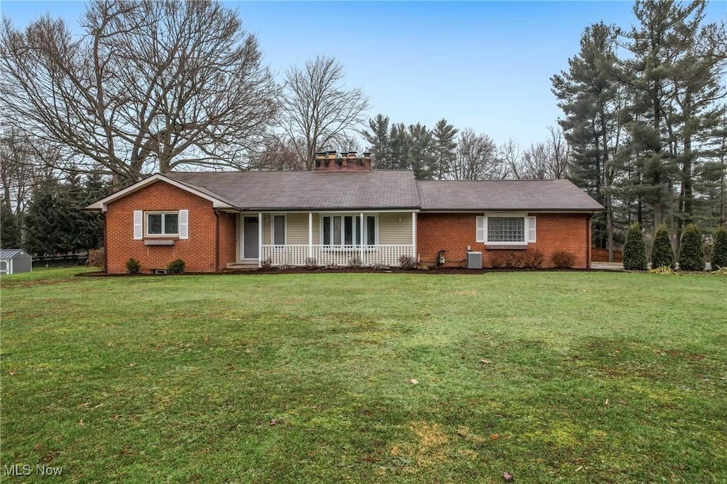 ranch-style home with a porch, a front yard, and central air condition unit