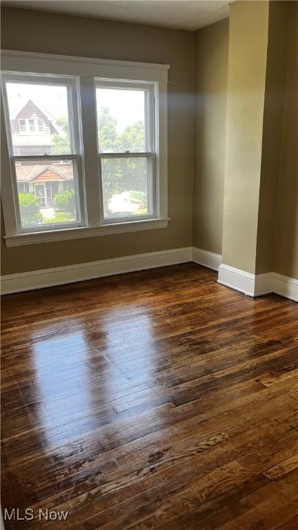 unfurnished room featuring a wealth of natural light and dark hardwood / wood-style floors