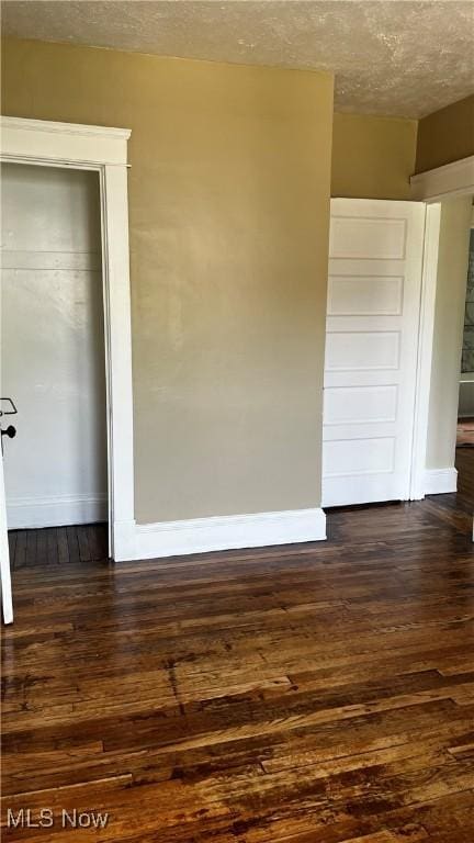 empty room with dark wood-type flooring and a textured ceiling