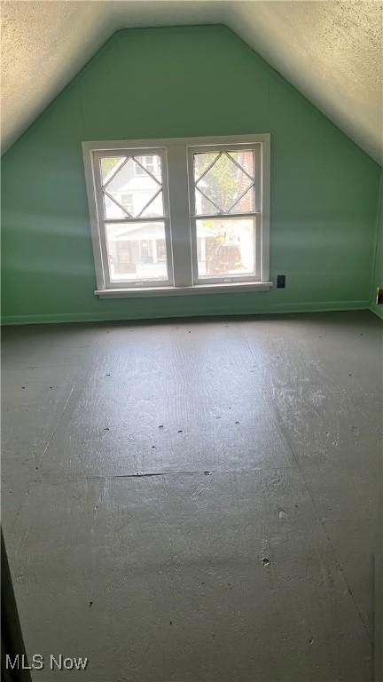 bonus room with lofted ceiling and a textured ceiling