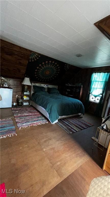 bedroom with vaulted ceiling and wood walls