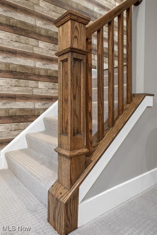 stairway featuring carpet flooring and wood walls