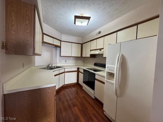 kitchen featuring white appliances, dark hardwood / wood-style flooring, sink, and a textured ceiling