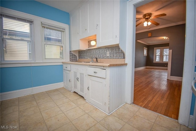 kitchen featuring sink, ceiling fan, backsplash, ornamental molding, and white cabinets