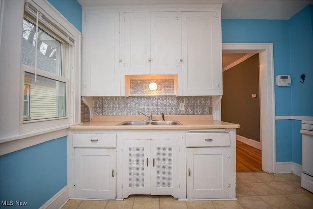 kitchen with tasteful backsplash, white cabinetry, and sink