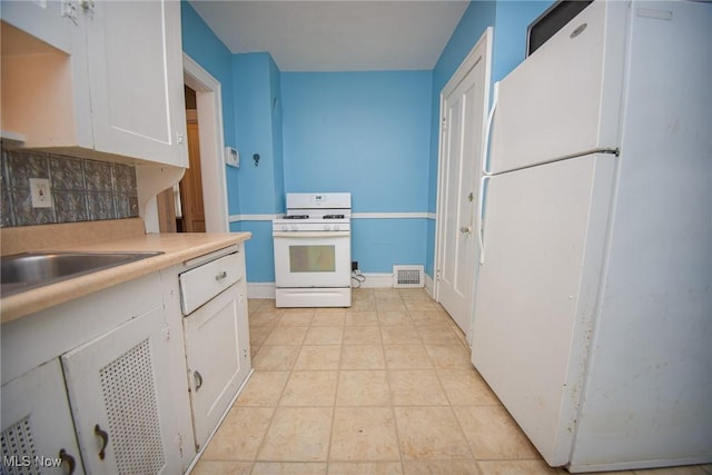 kitchen featuring sink, white appliances, white cabinets, light tile patterned flooring, and decorative backsplash