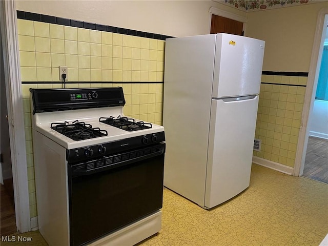 kitchen with tile walls, gas stove, and white refrigerator