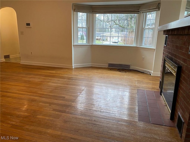 unfurnished living room with a brick fireplace, light hardwood / wood-style floors, and plenty of natural light