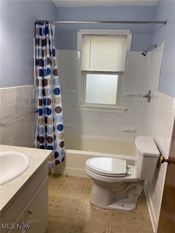 full bathroom with tile walls, shower / bath combination with curtain, vanity, and toilet