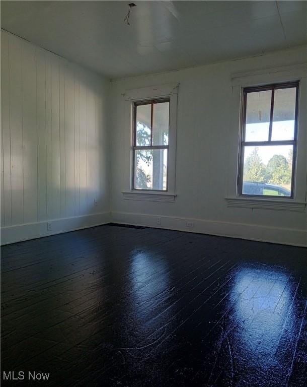 spare room with plenty of natural light and dark wood-type flooring