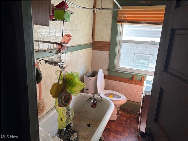 bathroom with parquet flooring, tile walls, and a tub to relax in