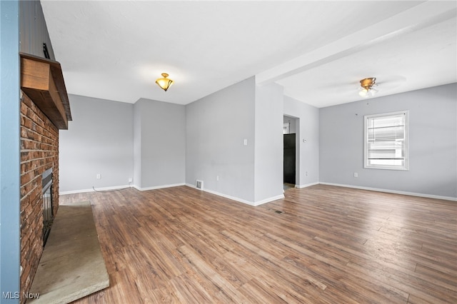 unfurnished living room featuring hardwood / wood-style flooring, ceiling fan, and a fireplace