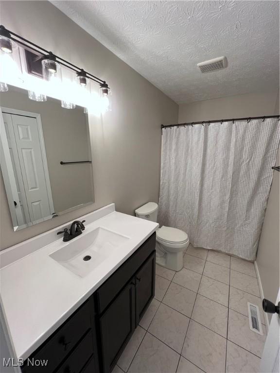 bathroom with vanity, tile patterned flooring, toilet, and a textured ceiling