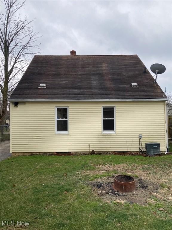 view of side of home featuring cooling unit, a lawn, and an outdoor fire pit