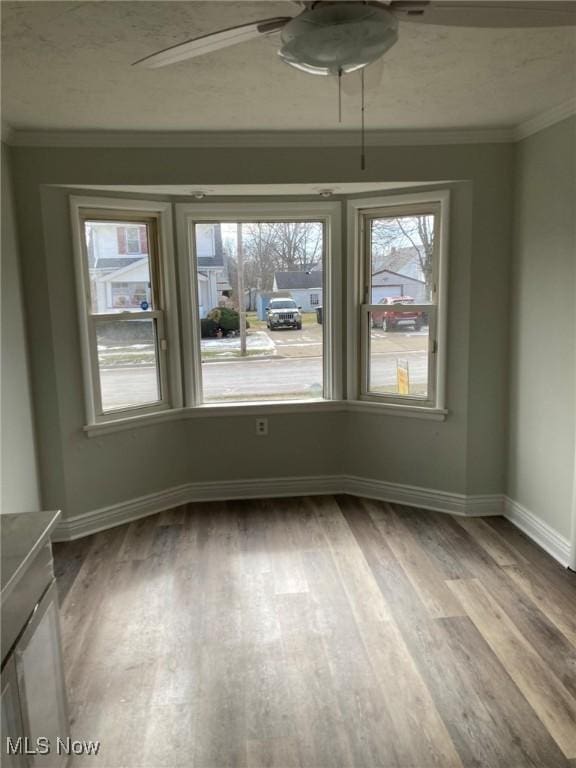 unfurnished room featuring crown molding, wood-type flooring, and ceiling fan