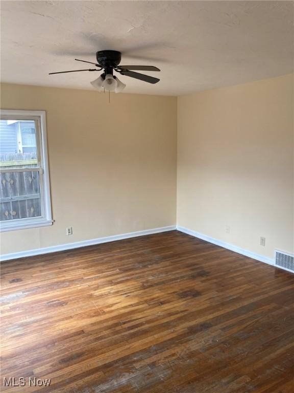 empty room featuring dark wood-type flooring and ceiling fan