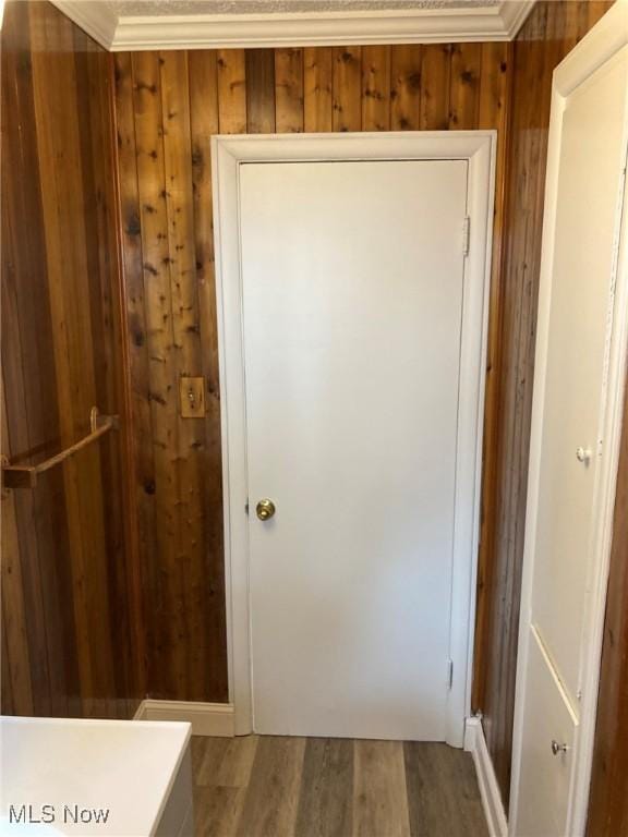 interior space with crown molding, wood-type flooring, and wooden walls