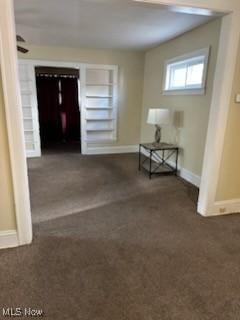 hall with dark colored carpet