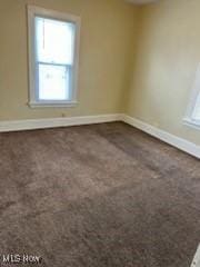 spare room featuring dark carpet