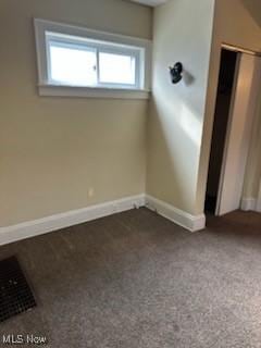 spare room with dark carpet