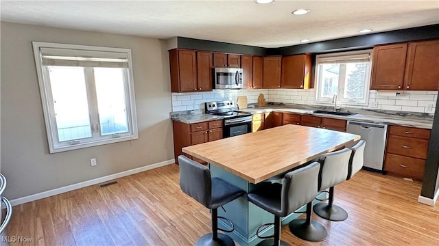 kitchen featuring sink, backsplash, light hardwood / wood-style floors, and appliances with stainless steel finishes