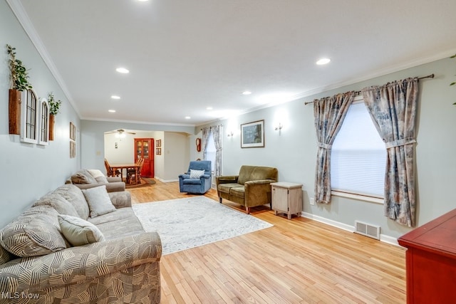 living room featuring crown molding, ceiling fan, and light hardwood / wood-style flooring