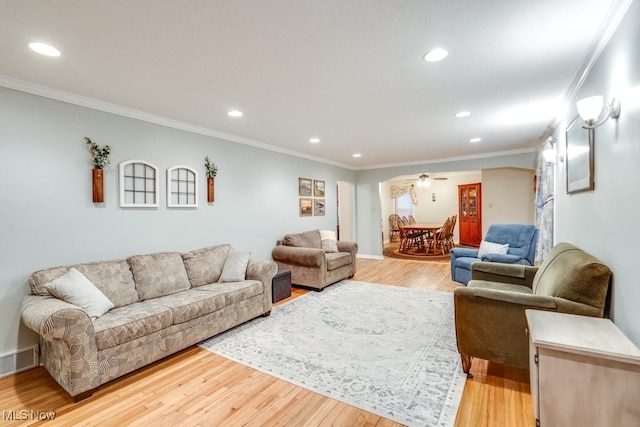 living room featuring ornamental molding, light hardwood / wood-style floors, and ceiling fan